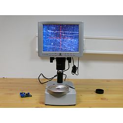 Aquí ve el microscopio para taller investigando una superficie metálica.