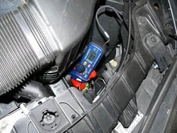 Usando el amperímetro de tenaza en la medición de un vehículo.