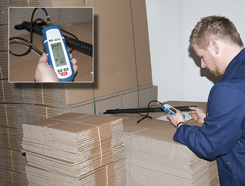 Aquí se muestra un especialista controlando una pila de cartón con el medidor de humedad universal.