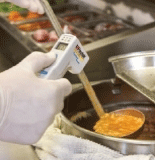 Medidor de temperatura sin contacto en alimentos midiendo la temperatura de la sopa.